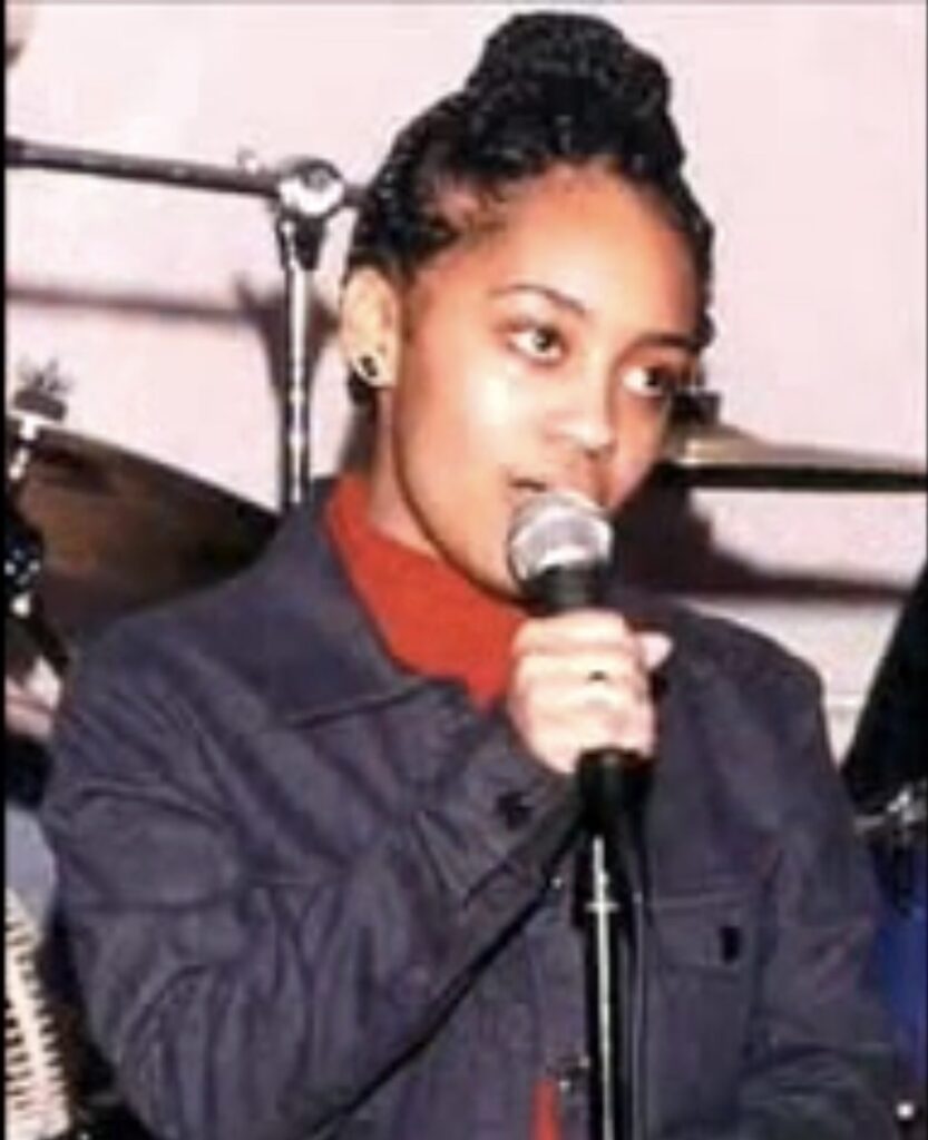 Tamika Huston is pictured on stage holding a microphone.